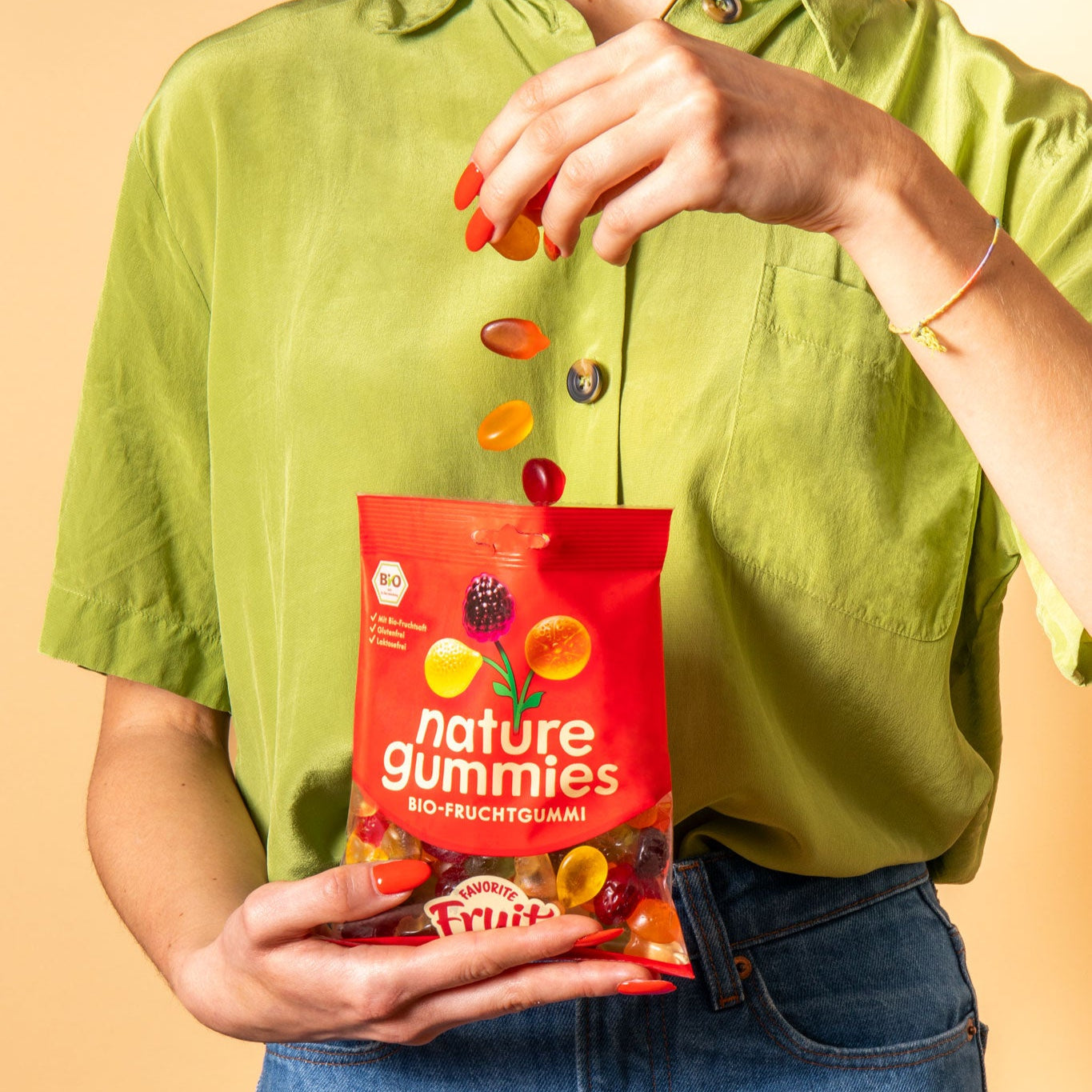 Person lässt die leckeren und fruchtigen Favorite Fruit Bio-Fruchtgummies von oben in eine Packung fallen.