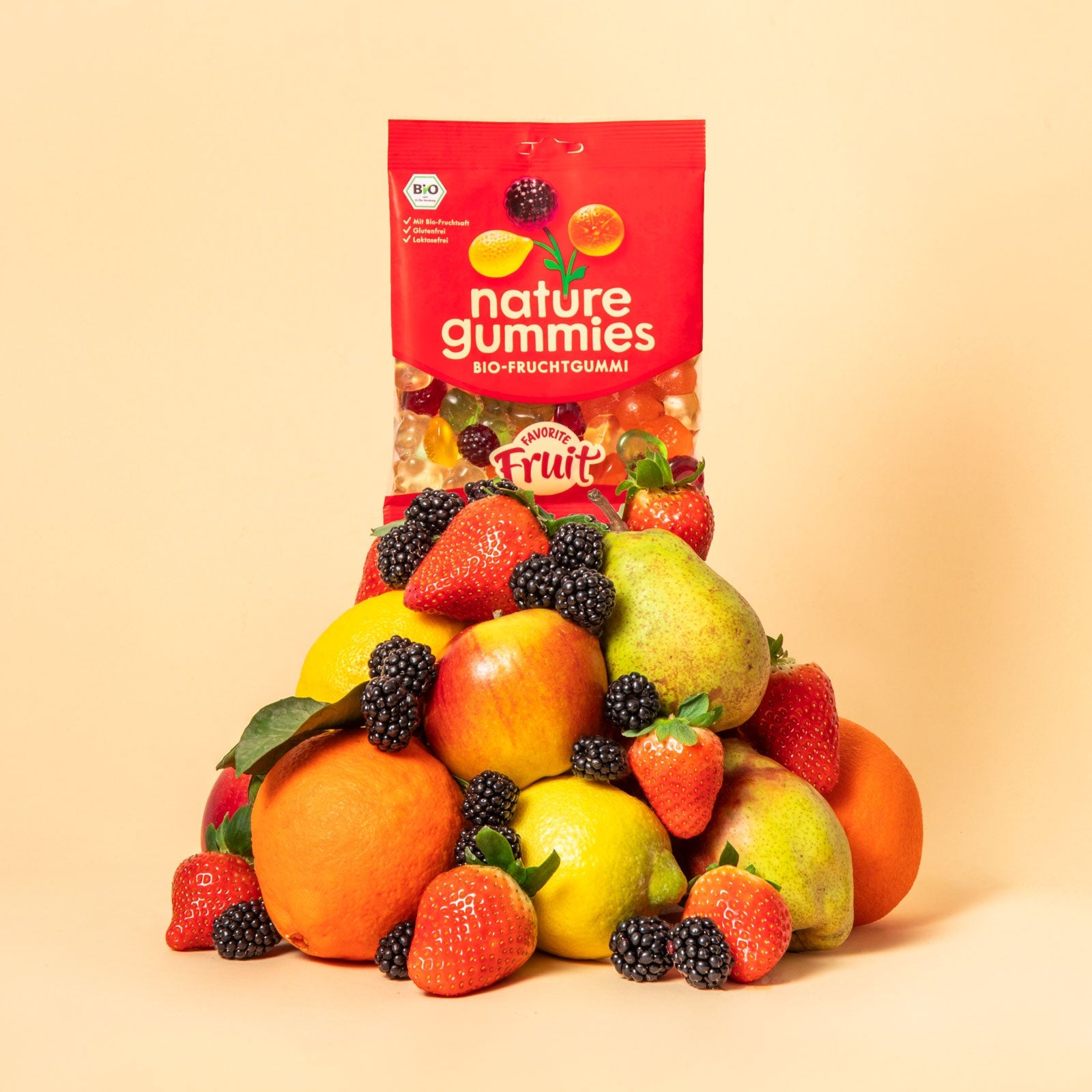 nature gummies Favorite Fruit Bio-Fruchtgummis auf einem Berg aus Früchten – Apfel, Orange, Brombeere, Erdbeere, Birne und Zitrone.