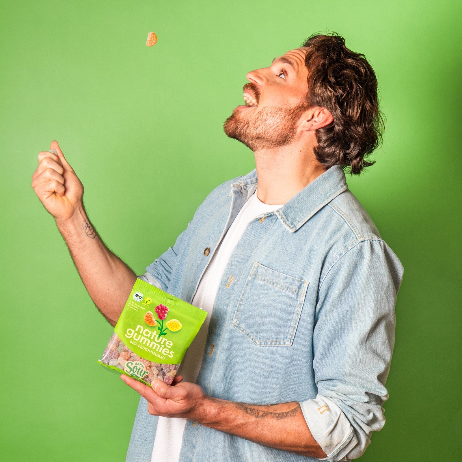 Ein Mann wirft ein Fruchtgummi der Sorte Happy Sour in die Luft und versucht es mit dem Mund aufzufangen – ein riesen Spaß.