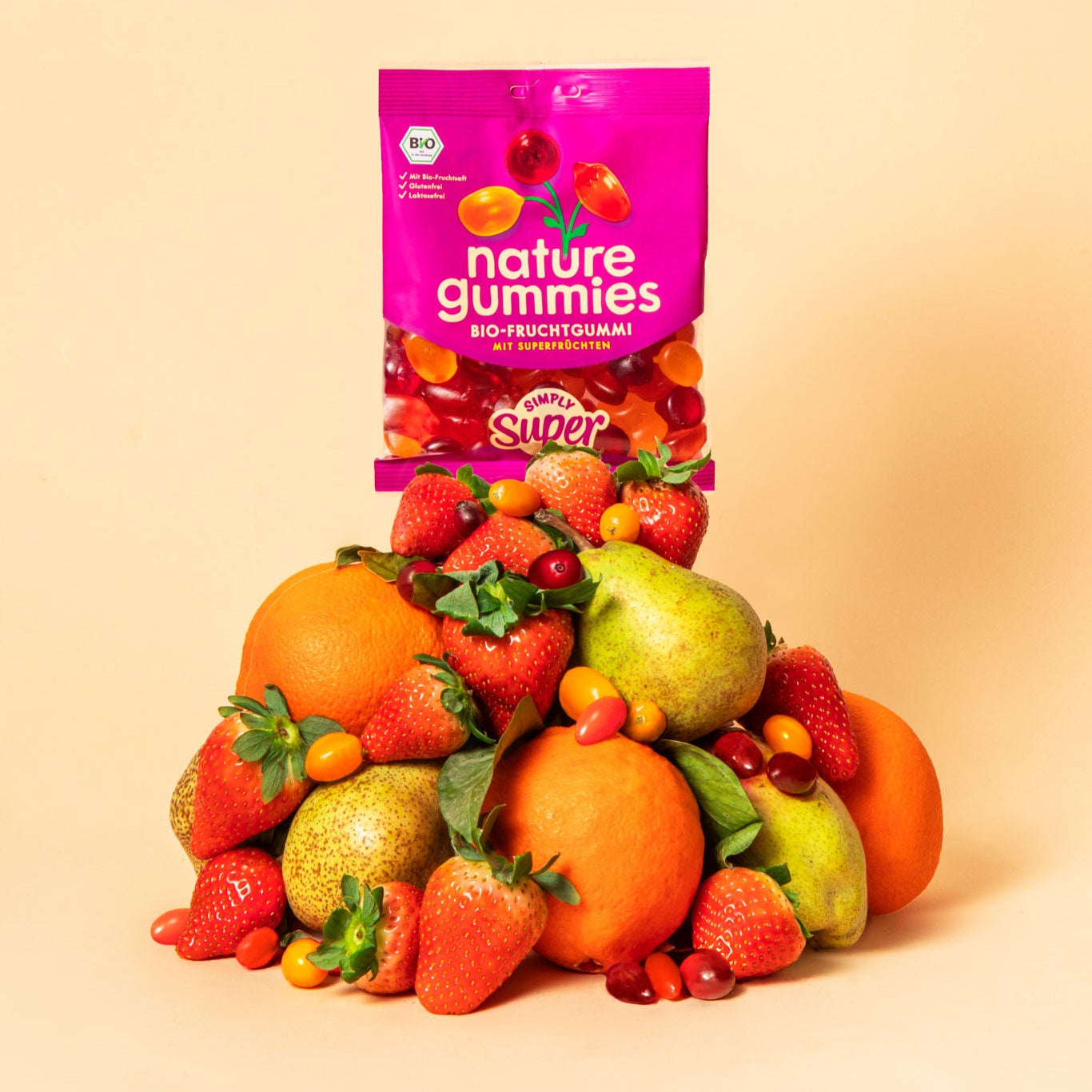 nature gummies Simlpy Super Bio-Fruchtgummis auf einem Berg aus Früchten – Orange-Sanddorn, Erdebeere-Gojibeere und Birne-Cranberry.
