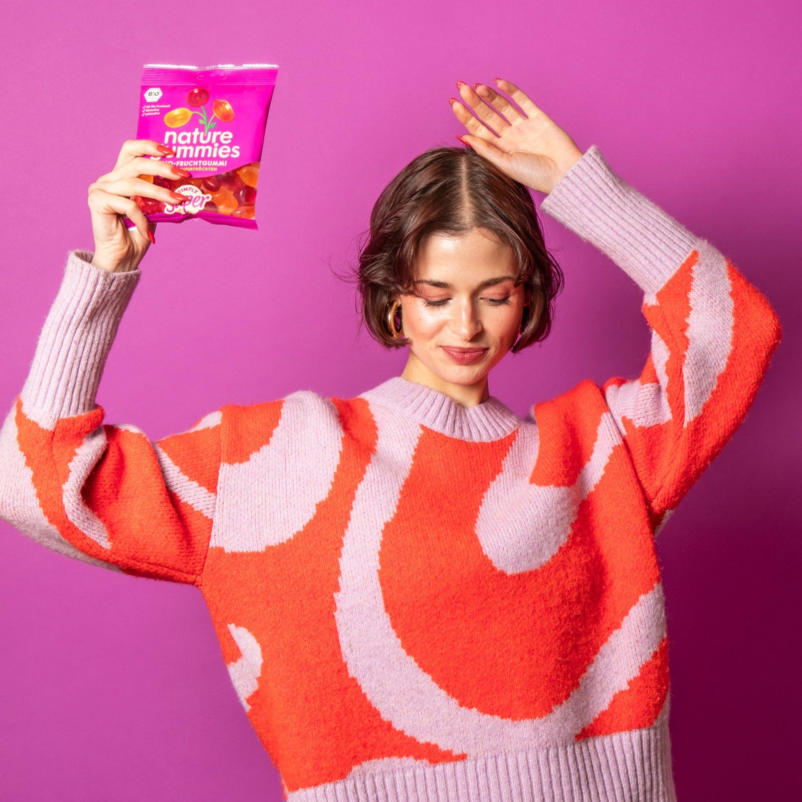 Eine Frau mit tanzt freudig und hält dabei eine nature gummies Packung der Sorte Simply Super in die Höhe. 