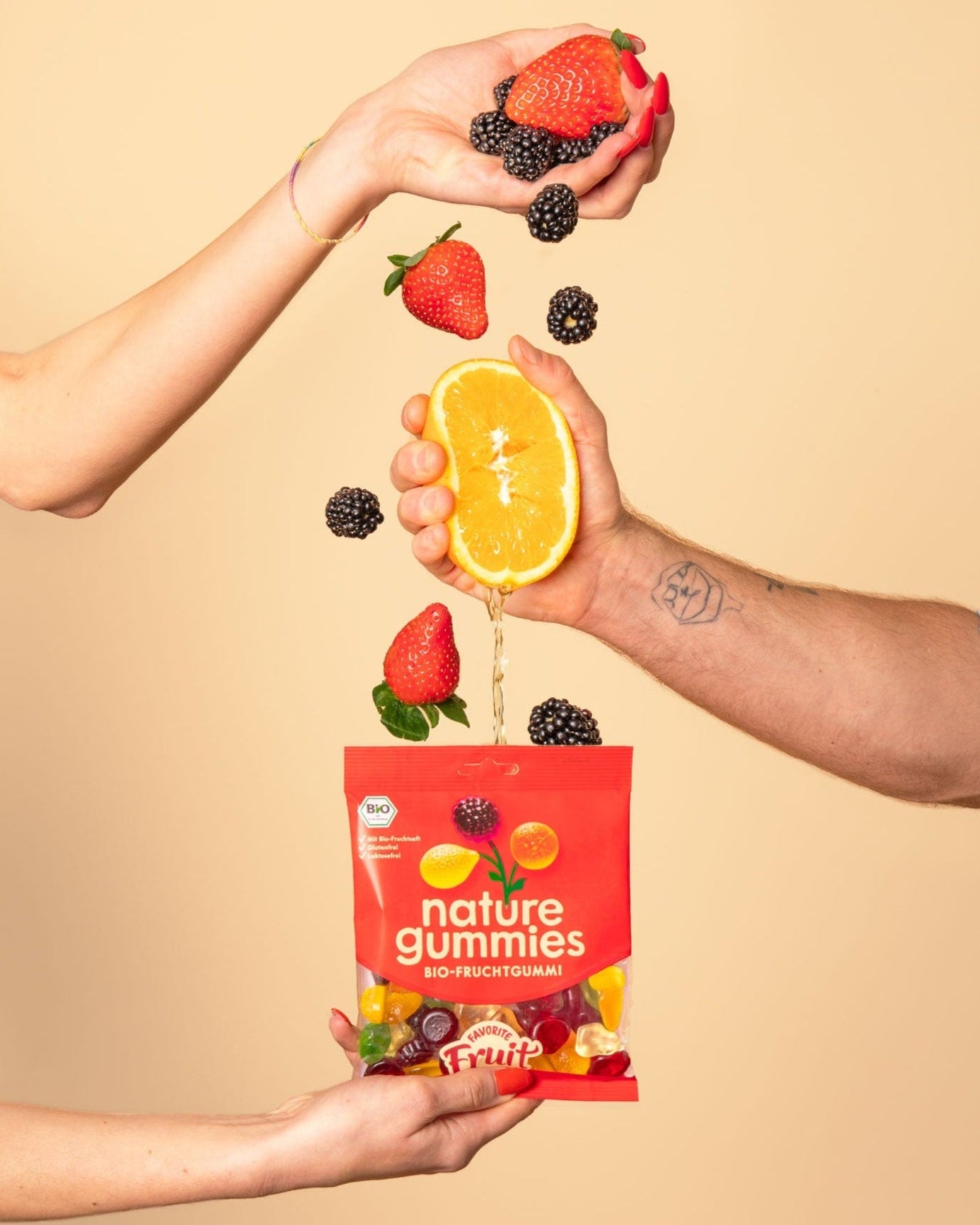 Hände pressen Saft aus Bio-Früchten in nature gummies Favorite Fruit Packung. 